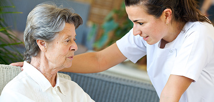 nurse leaning down to speak with a resident