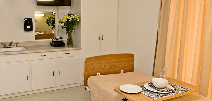 A resident room with a decorative food tray and flowers by the sink
