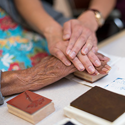 close up photo of activity director and a resident's hands doing an ink stamping craft project
