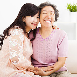 younger woman leaning in hugging an elderly woman