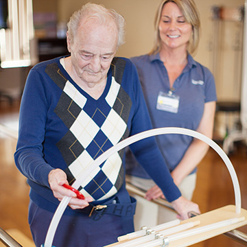 elderly man in sweater doing rehabilitation exercises
